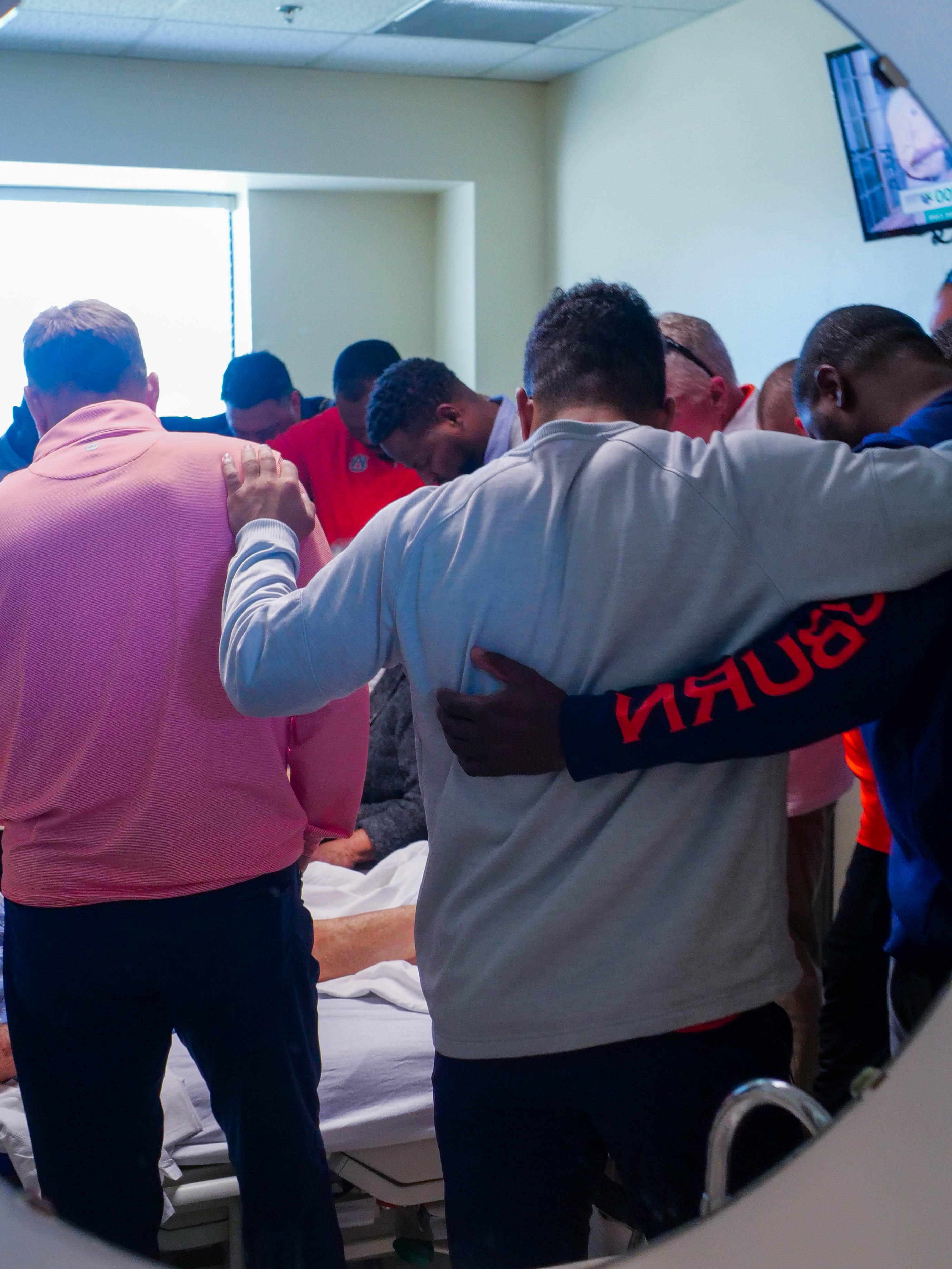 Auburn coaches pray with a patient at EAMC.