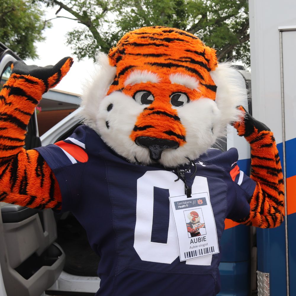 Aubie the Tiger poses for a photo while wearing an East Alabama Health badge.