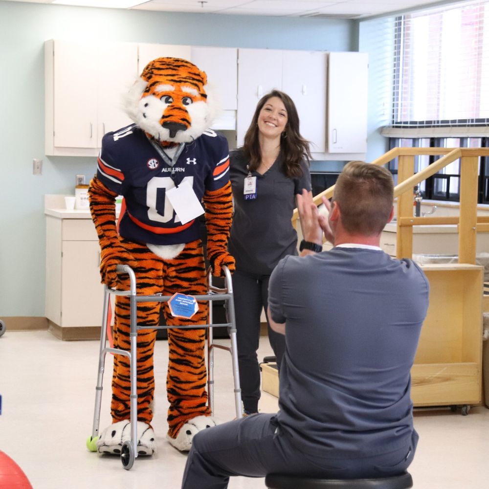 Aubie the Tiger working with physical therapists at East Alabama Medical Center.